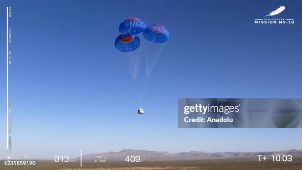 Screenshot taken from a live handout video on October 13, 2021 shows Blue Origin's New Shepard crew capsule returns in Texas, the United States....