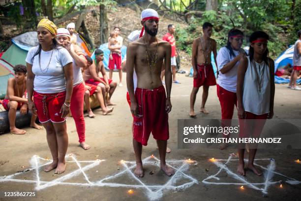 People stand inside white stars drawn on the pavement and surrounded by candles during a spiritual ceremony for good health on the Sorte mountain, in...