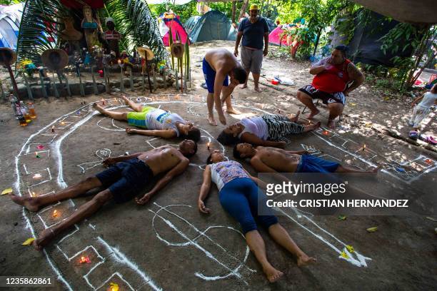 People lie inside a drawing on the pavement surrounded by candles during a ceremony asking for prosperity and protection, on the Sorte mountain, in...