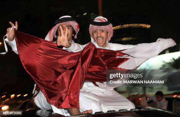 Qatari youths celebrate with a national flag in the streets of Doha after Qatar's football team won the gold medal match between Qatar and Iraq at...