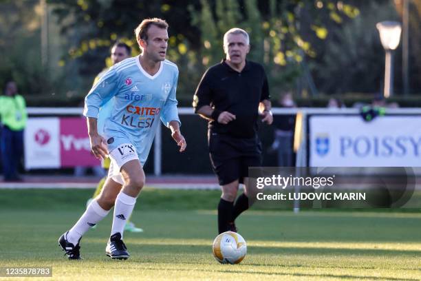 French President Emmanuel Macron plays the ball during a football match as part of the celebration of the fiftieth anniversary of the 'Varietes club...