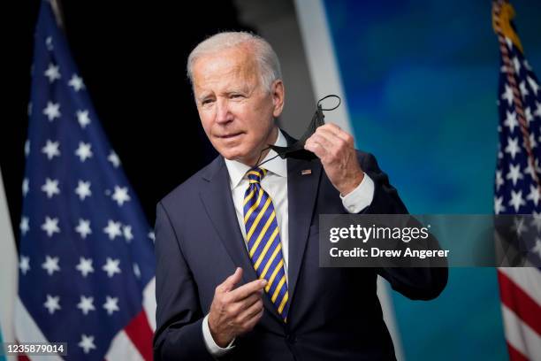 President Joe Biden removes his face mask as he arrives to speak in the South Court Auditorium on the White House campus October 14, 2021 in...