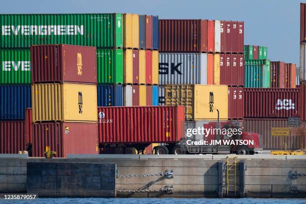 Truck driver passes stacked cargo containers at the Port of Baltimore in Baltimore, Maryland, on October 14, 2021. Closed factories, clogged ports,...