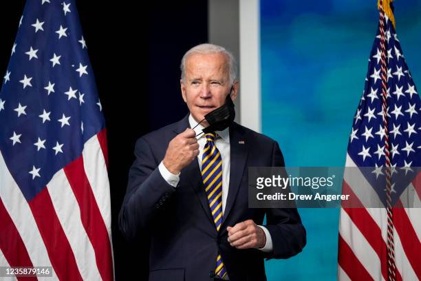 President Joe Biden removes his face mask as he arrives to speak in the South Court Auditorium on the White House campus October 14, 2021 in...