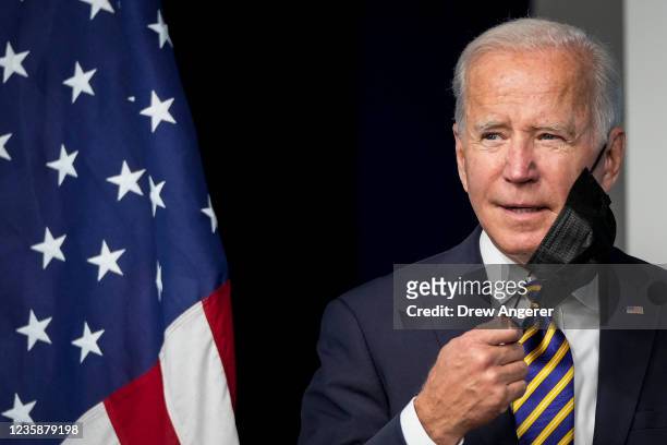 President Joe Biden removes his face mask as he arrives to speak in the South Court Auditorium on the White House campus October 14, 2021 in...