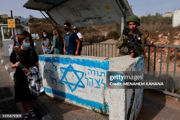 An Israeli soldier stand on guard as he keeps his position at a bus station at a road near the Jewish settlement of Ariel in the occupied West Bank...