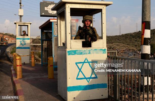 An Israeli soldier stand on guard as he keeps his position at a bus station at a road near the Jewish settlement of Ariel in the occupied West Bank...