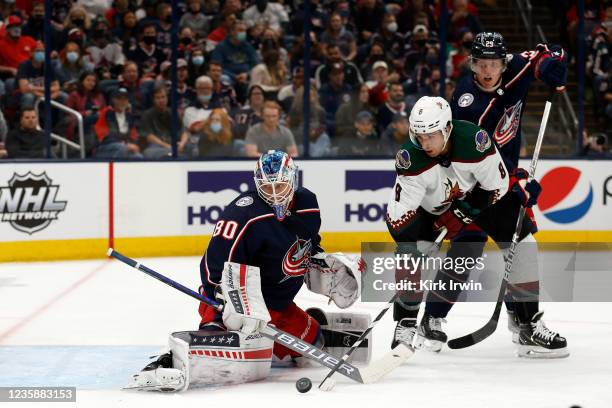 Elvis Merzlikins of the Columbus Blue Jackets makes a save with help form Patrik Laine on a shot by Nick Schmaltz of the Arizona Coyotes in the first...