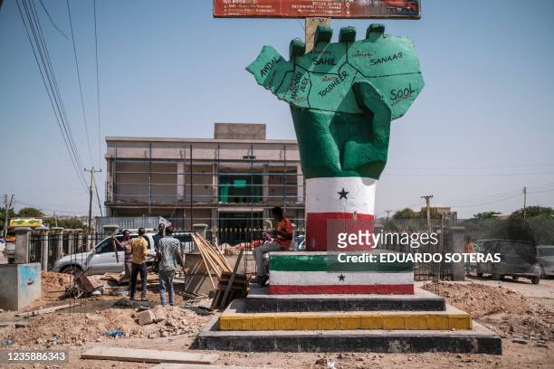 People stand next to the Independence Monument, depicting a hand holding a map of the country, in the city of Hargeisa, Somaliland, on September 19,...
