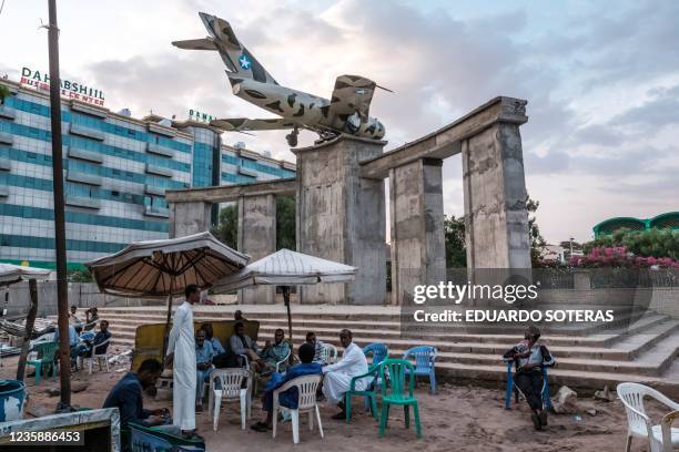 People sit at a coffee shop a the construction site of the Hargeisa War Memorial, currently under renovation, in the city of Hargeisa, Somaliland, on...