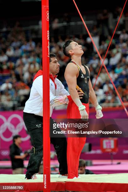 Marcel Nguyen representing Germany is helped up onto the horizontal bar by national coach Valeri Belenki before competing in the mens artistic team...