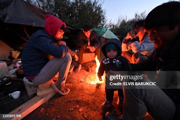 Afghan people are gathered around a fire at an illegal improvised camp, outside Northern-Bosnian border town of Velika Kladusa, on October 15, 2021....