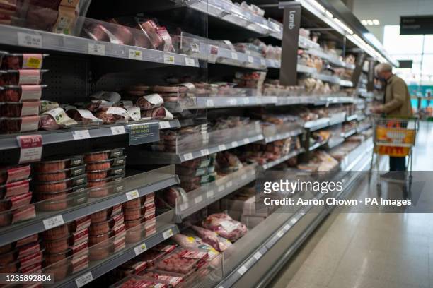 Shopper walks through the fresh meat aisle in a branch of Waitrose in south London. Shoppers are said to be buying a raft of Christmas items, such as...
