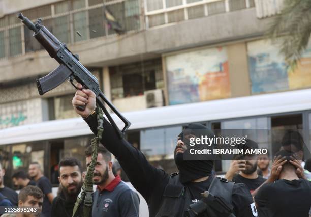 Member of Lebanon's Hezbollah movement fires his gun during the funeral of some of their members who were killed during clashes in the Tayouneh...