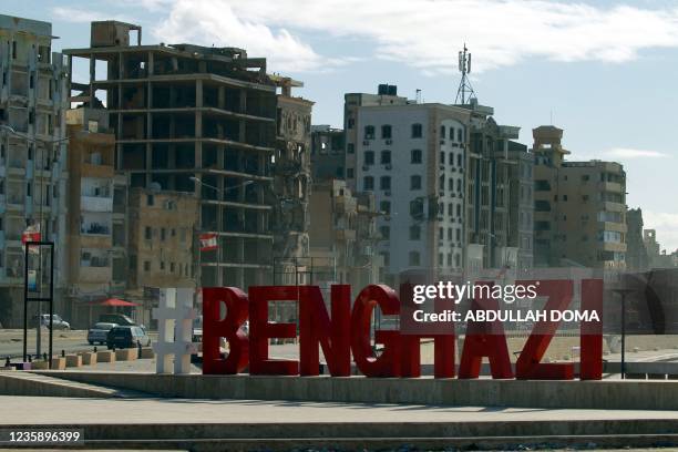 City name sign is pictured in front of war-ravaged buildings in Libya's eastern city of Benghazi, on October 15, 2021.