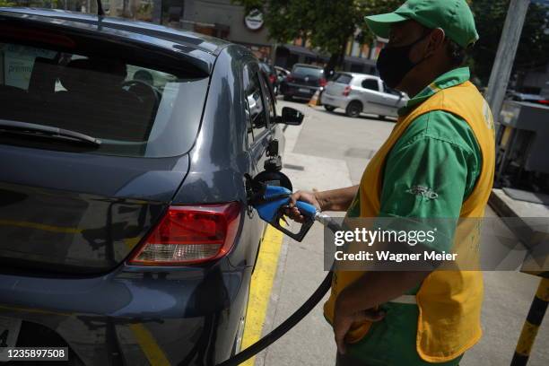 Petrobras employee fills the gas tank of a client at a Petrobras gas station at south zone Rio de Janeiro on October 15, 2021 in Rio de Janeiro,...