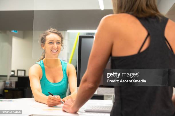 woman checking in behind plexi galss - gym reopening stock pictures, royalty-free photos & images