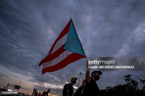 People march along Las Americas Highway as they hold Puerto Rican flags to demand the expulsion of power company Luma amid a continued lack of...