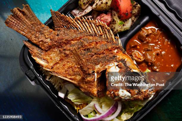Whole fried tilapia with sides of vegetables and khoresh bamieh and at Marhaba photographed in Tysons Corner, VA on October 13, 2021. .