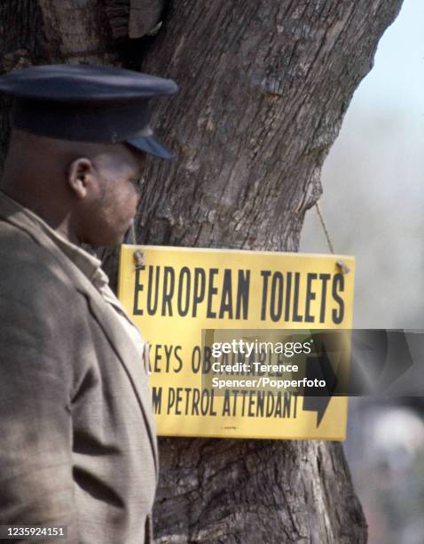 Black citizen passing a sign that reads "European Toilets" in Umzimkhulu, South Africa during Apartheid, circa 1970