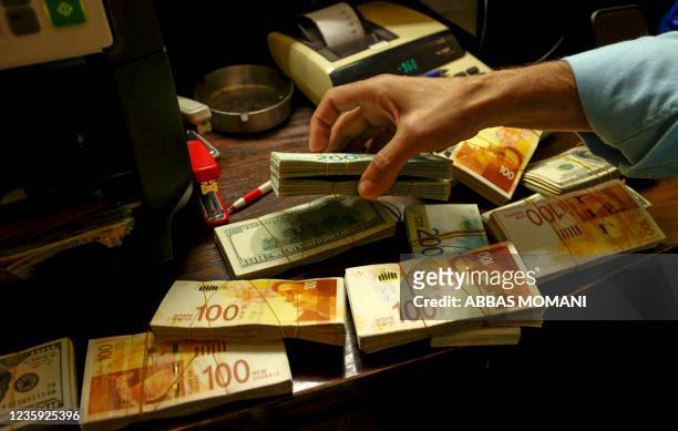 Palestinian man counts stacks of banknotes at a currency exchange counter in the West Bank city of Ramallah on October 5, 2021. - Palestinian...
