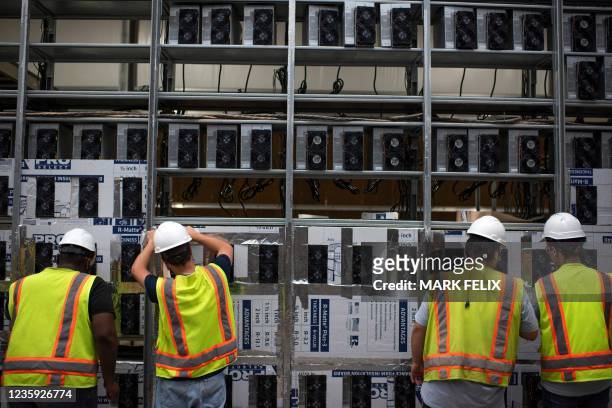 Workers install a new row of Bitcoin mining machines at the Whinstone US Bitcoin mining facility in Rockdale, Texas, on October 9, 2021. - The long...