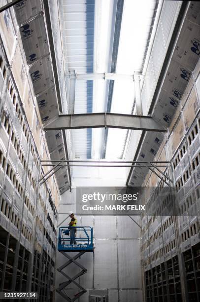 Worker installs a new row of Bitcoin mining machines at the Whinstone US Bitcoin mining facility in Rockdale, Texas, on October 9, 2021. - The long...