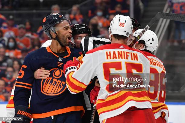 Darnell Nurse of the Edmonton Oilers scrums with Noah Hanifin and Andrew Mangiapane of the Calgary Flames on October 16, 2021 at Rogers Place in...