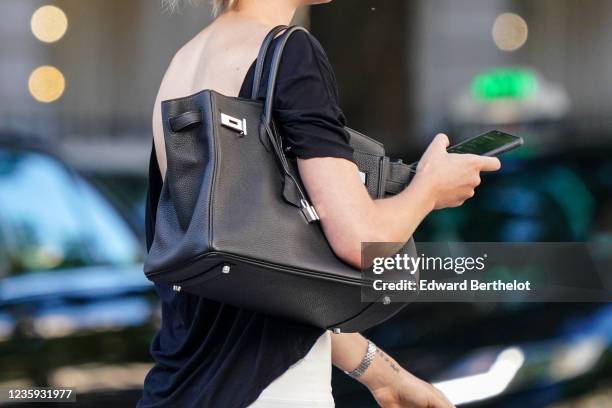 Passerby wears a black top, a black leather Hermes Birkin bag, on May 30, 2020 in Paris, France.