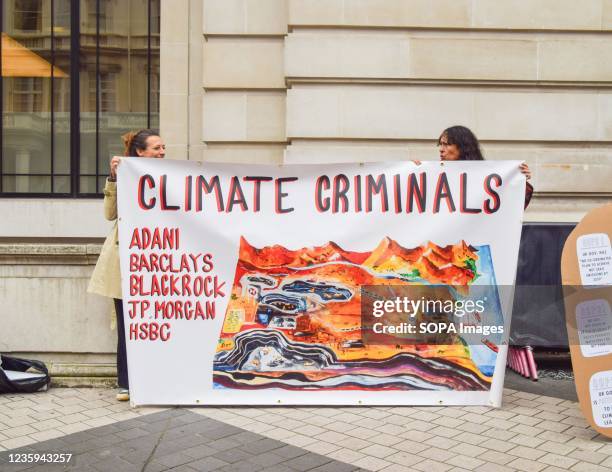 Activists hold a banner calling the companies Adani, Barclays, BlackRock, JP Morgan and HSBC "climate criminals", during the protest outside the...