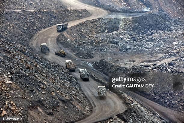 In this picture taken on October 14 trucks loaded with coal travel down a road at the Jharia coalfield in Dhanbad in India's Jharkhand state. -...