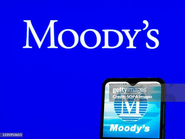 In this photo illustration, Moody's Investors Service logo seen displayed on a smartphone and in the background.