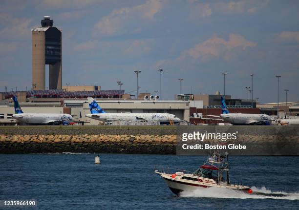 Pleasure boat on Boston Harbor passes jets parked at Boston's Logan International Airport on July 29, 2020.