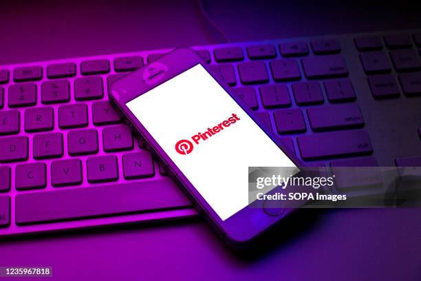 In this photo illustration a Pinterest logo seen displayed on a smartphone on top of a computer keyboard.