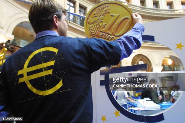 Une personne ajuste la reproduction d'une pièce de 10 euro, le 14 mai 2001 à la Bourse du commerce de Paris, lors de l'inauguration du salon de...