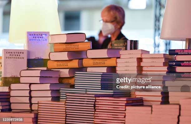 October 2021, Hessen, Frankfurt/Main: A woman stands in front of a pile of books on the sidelines of the Book Fair's opening press conference in the...
