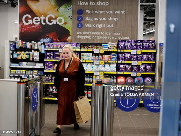 Customer carries the purchases as they leave from supermarket chain Tesco's first check-out free food store in Holborn, central London, on October...