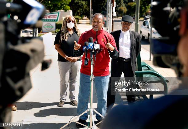 Social and political activist Najee Ali, center, joined by community activist Gina Fields, left, and Reverend Nathaniel Martin, right, speaks at a...