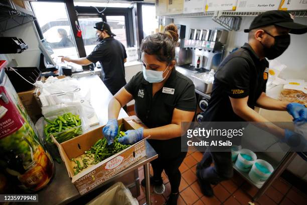 Juan Jimenez, left, at the drive-through window, general manger Maggie Briceno preparing peppers and Daniel Rodriguez, right, delivering food in the...