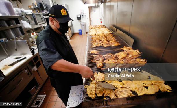 Cook Giovanni Gomez preparing chicken on the grill for food orders in the busy kitchen of the El Pollo Loco restaurant in Agoura Hills on August 18,...