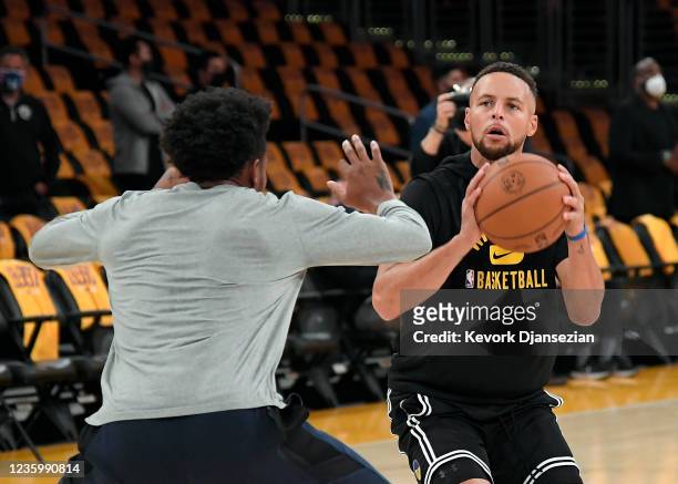 Stephen Curry of the Golden State Warriors guarded by player development coach Leandro Barbosa shoots during warm ups prior to the season opener...
