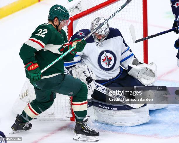 Connor Hellebuyck of the Winnipeg Jets makes a save as Kevin Fiala of the Minnesota Wild looks for the rebound in the third period at Xcel Energy...