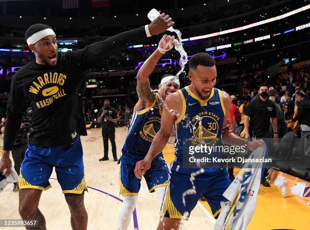 Stephen Curry of the Golden State Warriors is showered with water by his teammates Gary Payton II and Damion Lee as they celebrate after defeating...