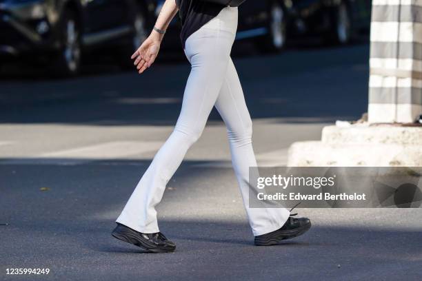 Passerby wears white tight flared leggings, black leather sneakers, on May 30, 2020 in Paris, France.