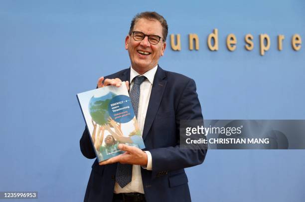 German Development Minister Gerd Mueller poses with Germany's international development policy report during a press conference on its presentation...
