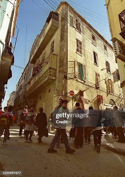 Des écoliers passent devant l'immeuble natal du chanteur juif pied-noir Enrico Macias, le 21 février 2000 dans la Casbah de Constantine. Enrico...