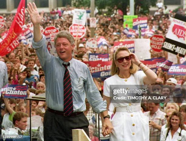 Democratic presidential candidate Bill Clinton waves to supporters as he holds the hand of his wife Hillary, 22 July, 1992 after speaking at a rally....