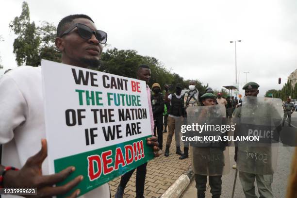 Man displays a placard during a protest to commemorate one year anniversary of EndSars, a protest movement against police brutality at the Unity...