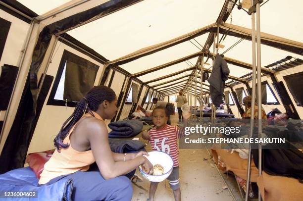 Une femme donne à manger à son enfant sous une tente, le 05 septembre 2005 dans un campement provisoire, dit "de la Fraternité", installé dans le...