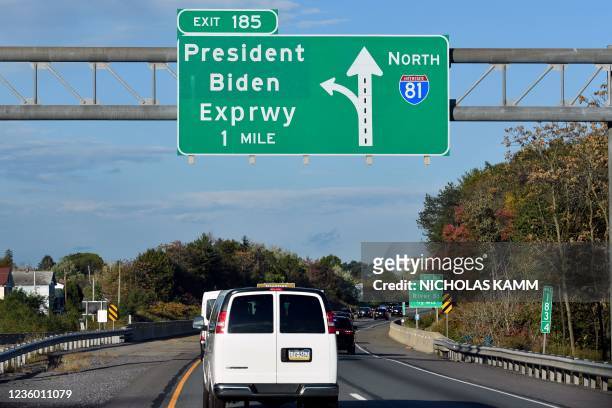 President Joe Biden's motorcade drives past a traffic sign of President Biden Expressway as he promotes the Bipartisan Infrastructure Deal and Build...